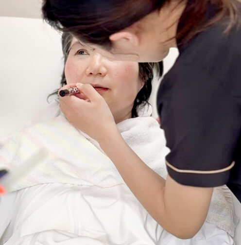 ベッド上でメイク施術を受ける女性